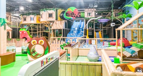 Colorful indoor play area featuring slides, climbing structures, and soft play equipment for children.