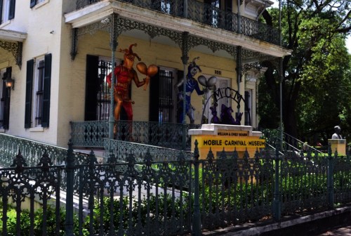 Exterior of the Mobile Carnival Museum, featuring colorful jester figures and ornate ironwork.
