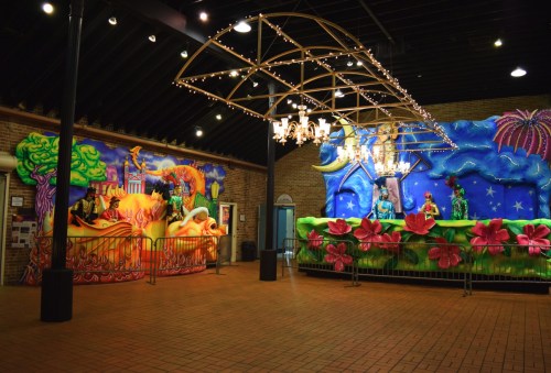 Colorful floats and decorations in a festive indoor space, featuring vibrant designs and lights.