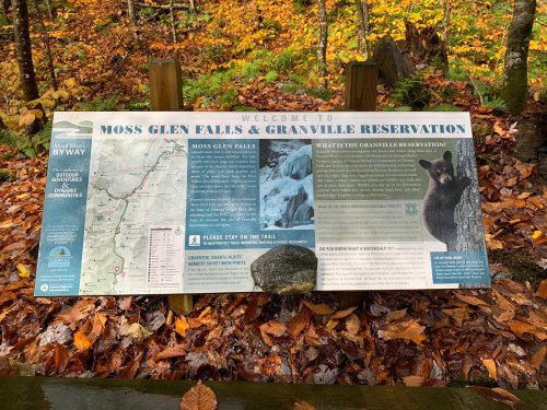 Sign welcoming visitors to Moss Glen Falls and Granville Reservation, surrounded by autumn foliage and a bear illustration.