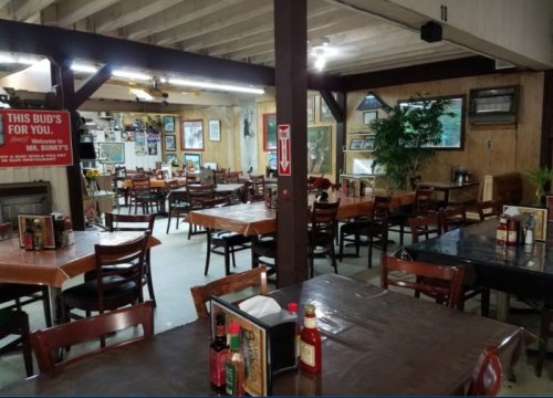 Interior of a casual restaurant with wooden tables, chairs, and decor on the walls, creating a cozy atmosphere.