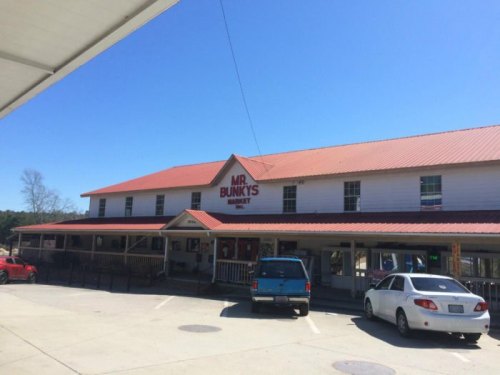 Exterior of Mr. Bunky's Market, a two-story building with a red roof and parked cars in front under a clear blue sky.