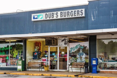 Exterior of Dub's Burgers, featuring a sign, benches, and a storefront with a welcoming atmosphere.