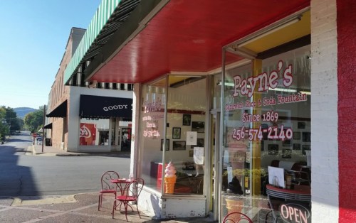 Exterior view of Payne's Soda Fountain, featuring a red and white facade, outdoor seating, and an ice cream cone sign.