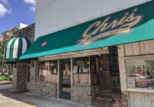 Exterior of Chris's restaurant with a green awning, stone facade, and striped entrance canopy.
