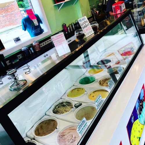 A colorful ice cream display with various flavors in tubs, set in a bright shop with a cheerful atmosphere.
