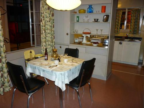 A retro kitchen scene featuring a dining table set with dishes, chairs, and colorful curtains in a cozy atmosphere.
