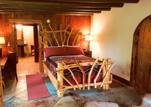 Cozy bedroom featuring a unique wooden bed frame, warm lighting, and rustic decor in a natural setting.