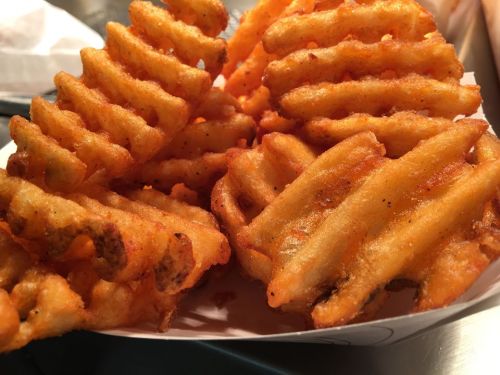 A close-up of golden-brown waffle fries arranged in a serving tray.
