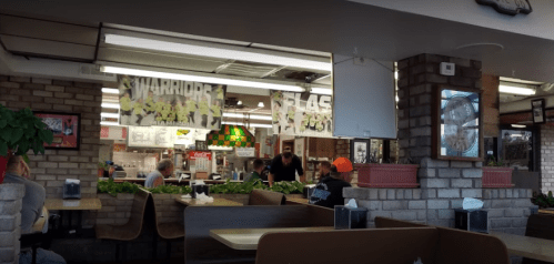 A casual dining area with brick walls, tables, and customers enjoying their meals in a lively atmosphere.
