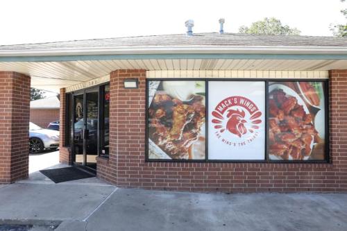 Exterior of a restaurant featuring large windows with images of wings and the name "Mack's Wings" displayed prominently.