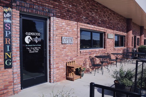 Exterior of Farmhouse Fresh with a brick facade, open sign, and outdoor seating area. Spring decor visible.