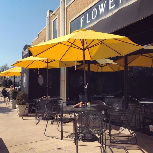 Outdoor café scene with yellow umbrellas, black tables, and chairs, set against a sunny backdrop.