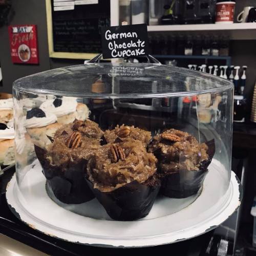A glass display case featuring German chocolate cupcakes topped with coconut frosting and pecans.