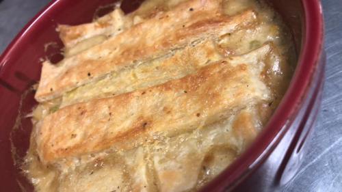 Bowl of baked dish with golden-brown crust and bubbling filling, likely a casserole or savory pie.