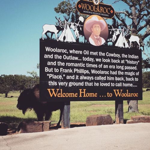 Sign for Woolaroc Museum & Wildlife Preserve, featuring a cowboy and bison in the background, highlighting its historical significance.