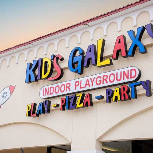 Colorful sign for "Kid's Galaxy" indoor playground featuring play, pizza, and party activities.