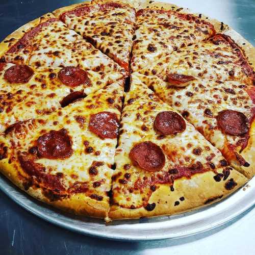 A freshly baked pepperoni pizza with melted cheese, sliced into eight pieces on a silver pizza tray.