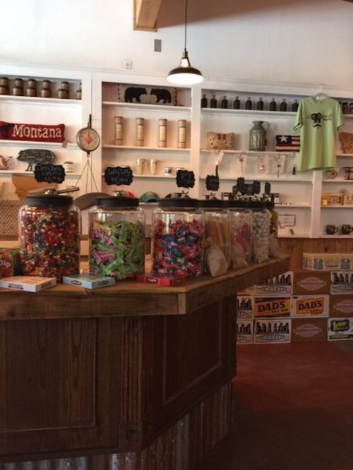 A cozy candy shop with colorful jars of sweets on a wooden counter and vintage decor on the walls.