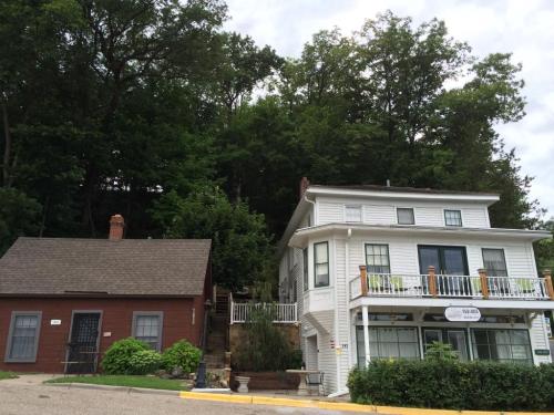 Two houses sit side by side, one brown and one white, with a lush green hillside in the background.