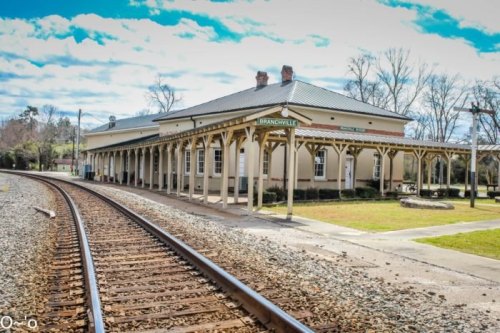Historic train station in Branchville, SC, with a platform and tracks under a clear blue sky.