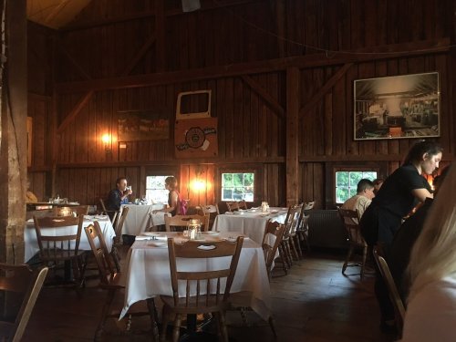 Cozy restaurant interior with wooden walls, tables set for dining, and warm lighting creating an inviting atmosphere.