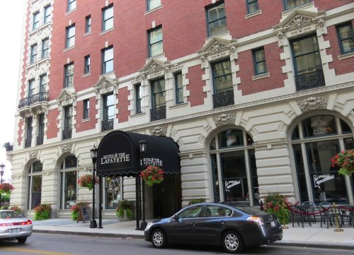 Historic Hotel Lafayette with red brick facade, ornate details, and flower planters, located on a city street.