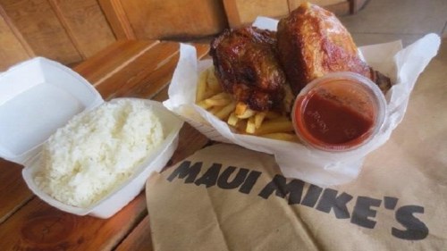 A plate of crispy chicken with fries and a side of rice, accompanied by a small container of sauce. Maui Mike's branding visible.
