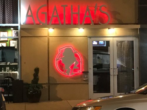 A restaurant sign reading "AGATHA'S" with a red silhouette logo on the wall, illuminated at night.