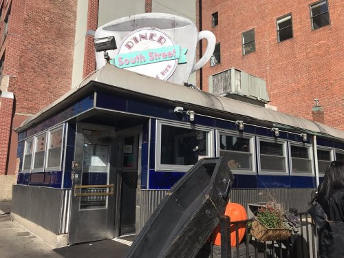 A classic diner with a blue exterior and a large coffee cup sign, located on South Street.