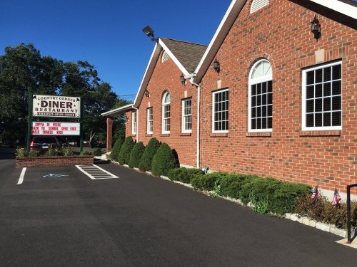 Exterior of Country Corner Diner, featuring a brick building, large windows, and a sign with menu details.