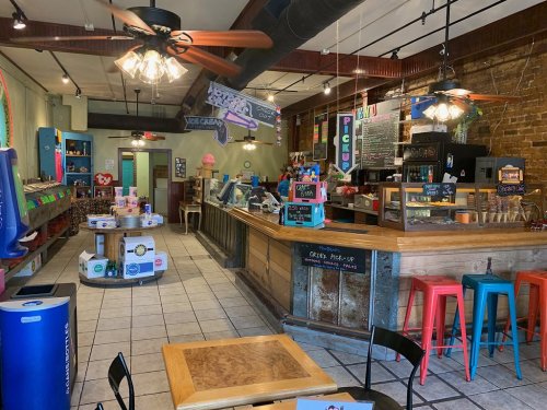 A cozy ice cream shop with colorful decor, a wooden counter, and various ice cream flavors displayed.