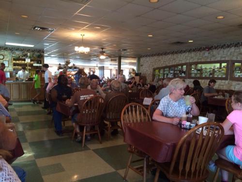 A busy restaurant interior with patrons seated at tables, chatting and enjoying meals in a casual atmosphere.