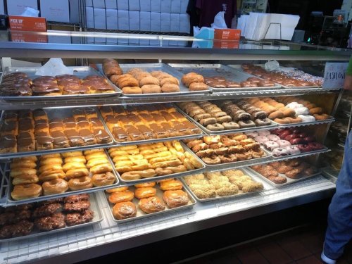 A display case filled with various types of donuts, including glazed, chocolate, and filled varieties.