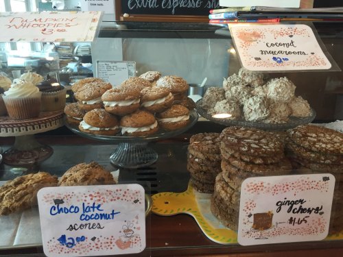 A display case filled with baked goods: pumpkin whoopie pies, coconut macaroons, scones, and ginger chews.