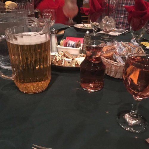 A table setting with a pitcher of beer, a glass of rosé, and a plate of snacks in a restaurant.
