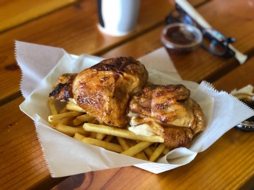 A basket of golden-brown fried chicken pieces served with crispy French fries on a wooden table.