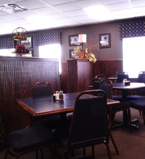 Cozy restaurant interior with wooden tables, chairs, and decorative elements on the walls and shelves.