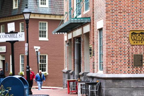 A street view featuring brick buildings, a lamppost, and a man walking near a sign for Cornhill Street.