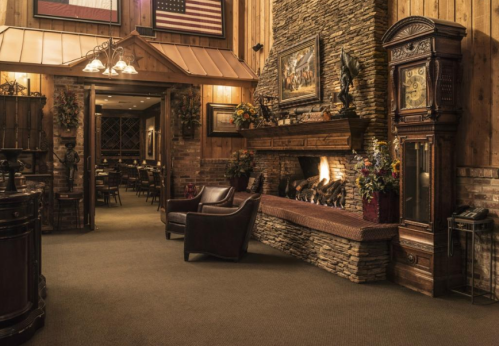 Cozy interior with a stone fireplace, wooden walls, and elegant seating, creating a warm, inviting atmosphere.