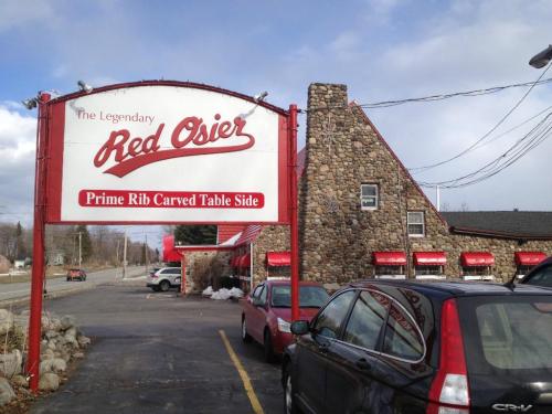 Sign for Red Osier restaurant with stone building and parked cars, set against a cloudy sky.