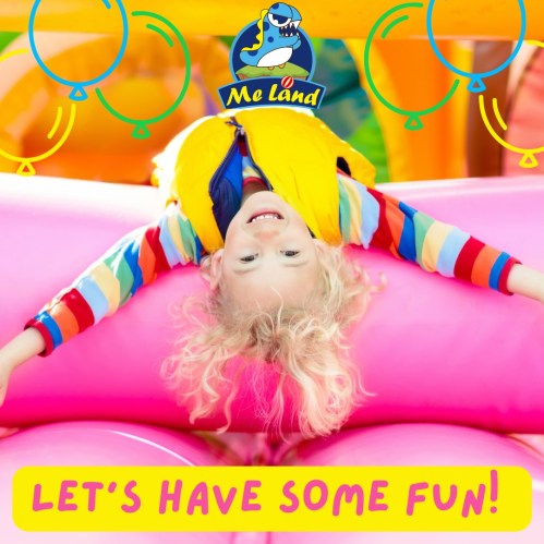 A joyful child in a colorful outfit plays upside down on a soft surface, surrounded by bright, playful decorations.