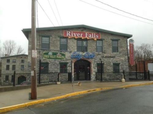 Stone building with "River Falls" sign, featuring free valet parking and a blue "Lily Suite" sign.