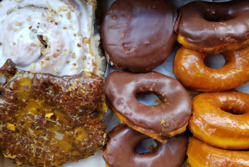 A box of assorted donuts: chocolate-glazed, glazed, and a cinnamon roll topped with nuts.