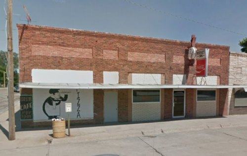 A brick building with a sign for a cafe and a mural of a chef, featuring a covered porch and a Coca-Cola sign.