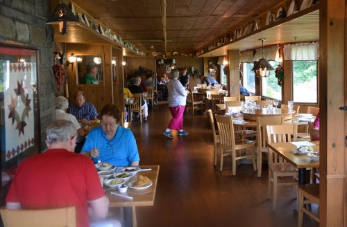 A cozy restaurant interior with diners enjoying meals at wooden tables, surrounded by rustic decor and warm lighting.