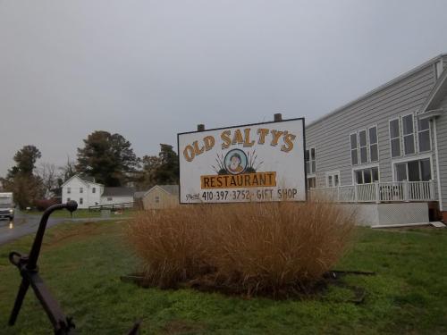 Sign for Old Salty's Restaurant and Gift Shop, surrounded by tall grass and a cloudy sky.