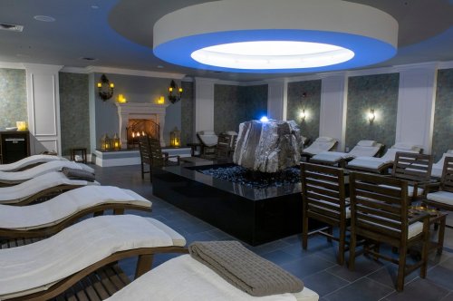 A serene spa room with lounge chairs, a stone centerpiece, and soft lighting, creating a relaxing atmosphere.