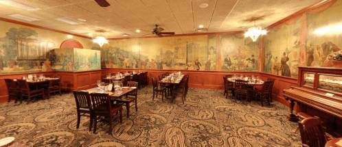 A cozy restaurant interior with wooden tables, chairs, and colorful mural-covered walls. Elegant decor and soft lighting.