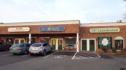 A row of businesses including a Chinese restaurant, a breakfast spot, and a laundromat in a brick building.